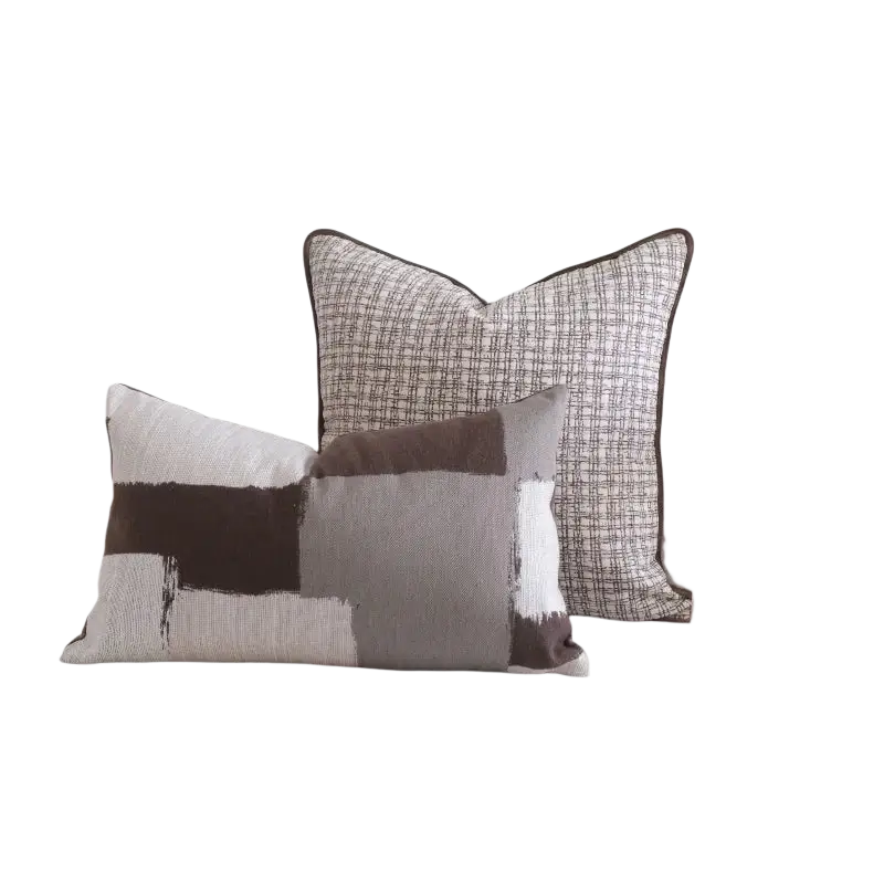 Two rectangular throw pillows with brown maillard geometric jacquard cushion covers on a light-colored sofa