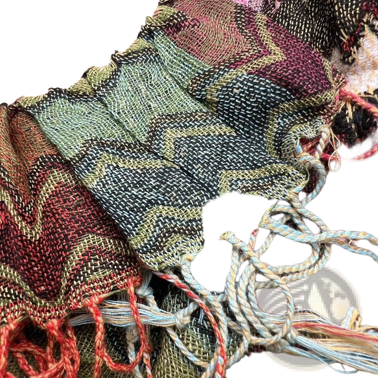 Geometric knit scarf with zigzag pattern in earthy green black and rust tones featuring red fringe tassels and frayed edges