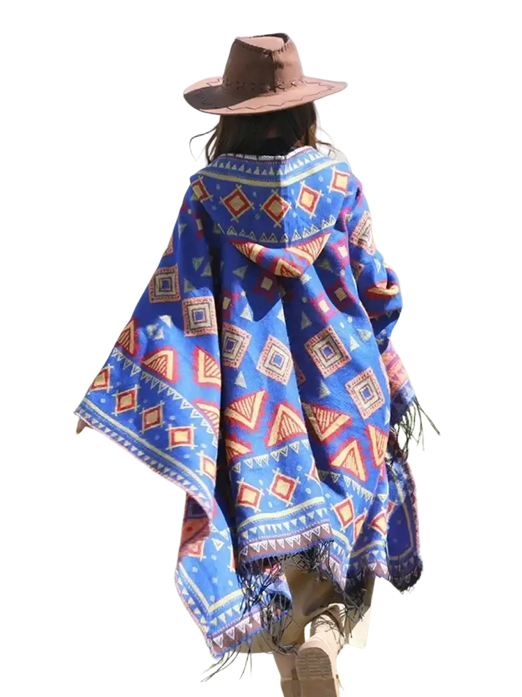 A vibrant blue knitted hooded poncho cape with red orange and white geometric patterns and fringed edges
