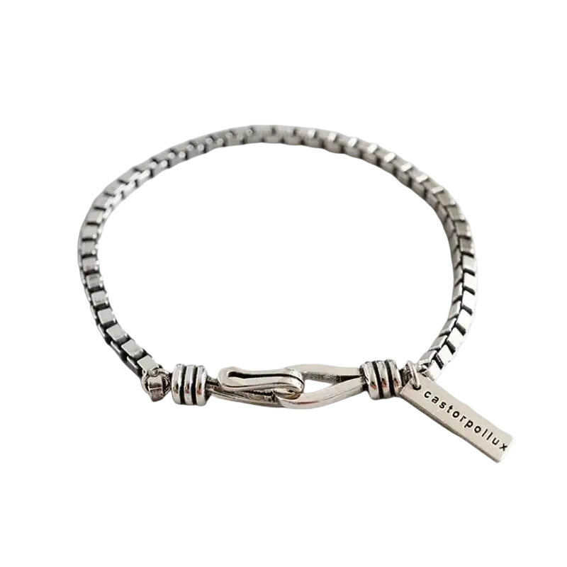 Picture shows a silver-toned geometric metal charm bracelet for couples with toggle clasp and engraved tag castorpollux