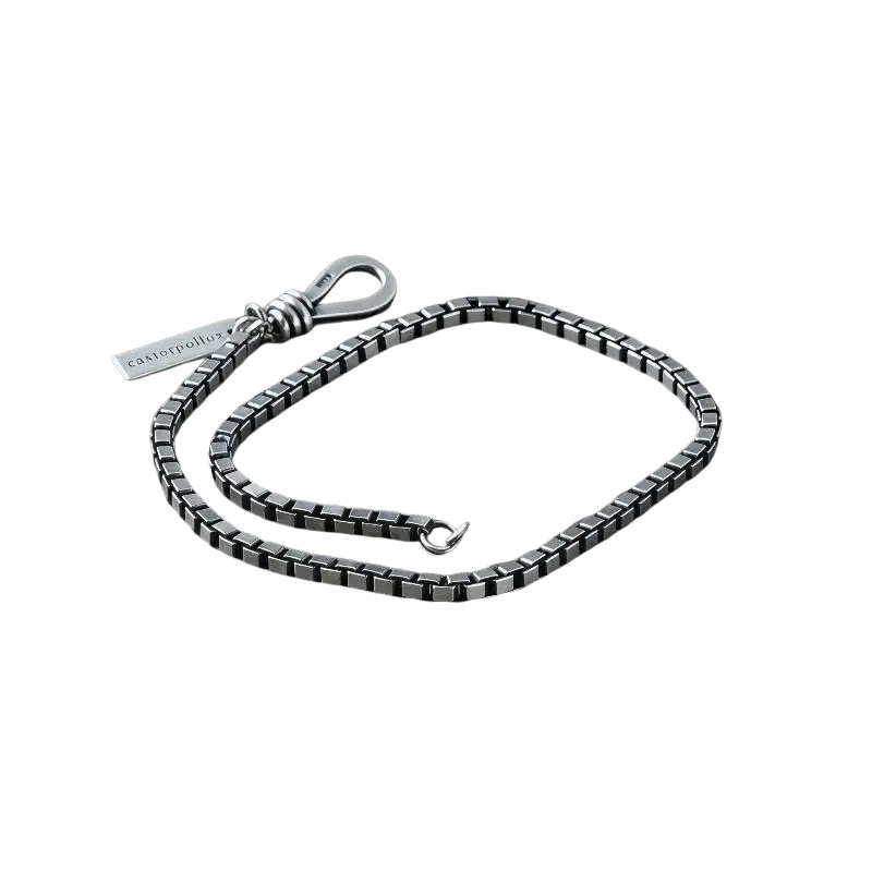 The picture shows a silver-toned geometric metal charm bracelet for couples with black silver checkered links and branded tag