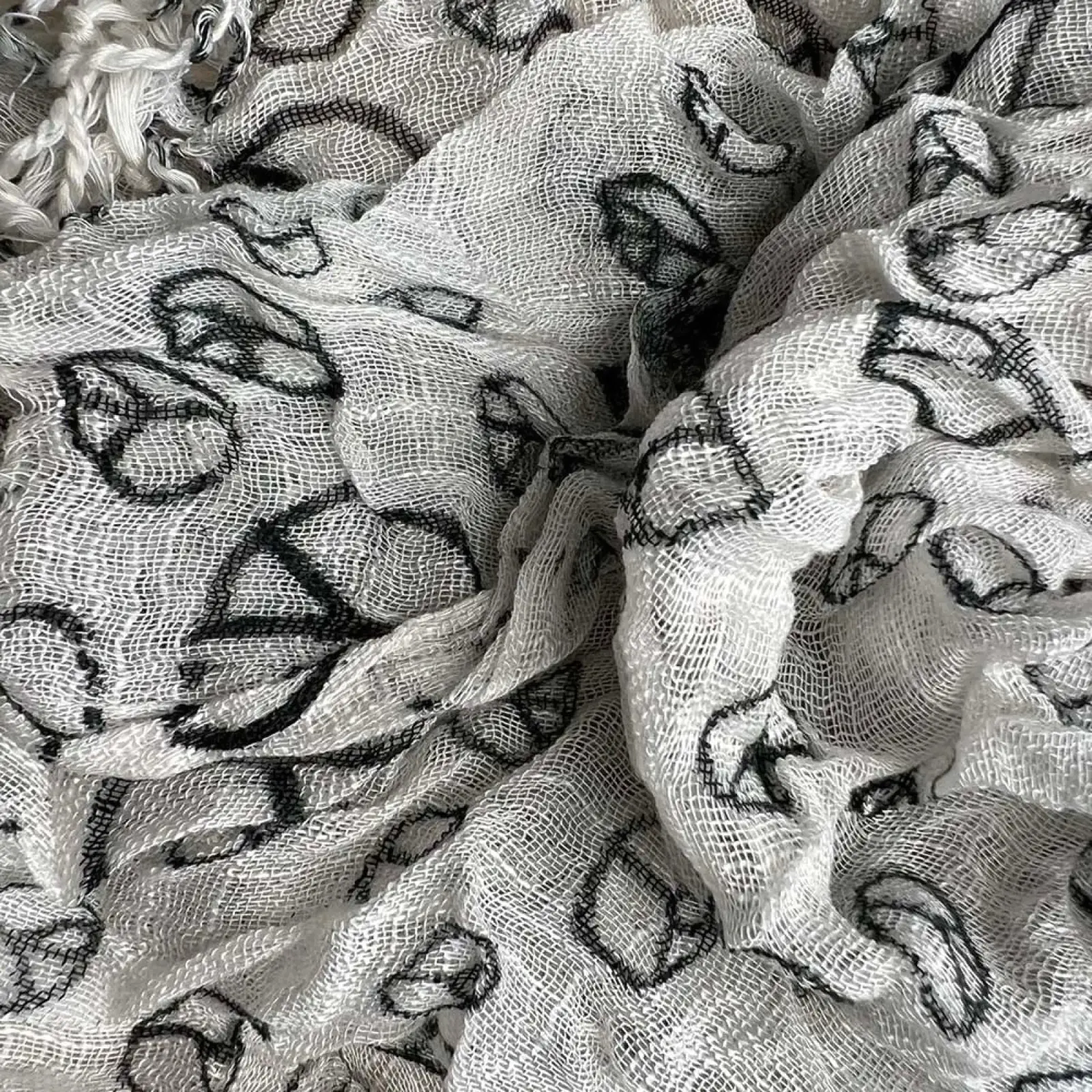 A delicate white viscose mesh scarf with a repeating pattern of black embroidered lips titled geometric peace sign viscose scarf