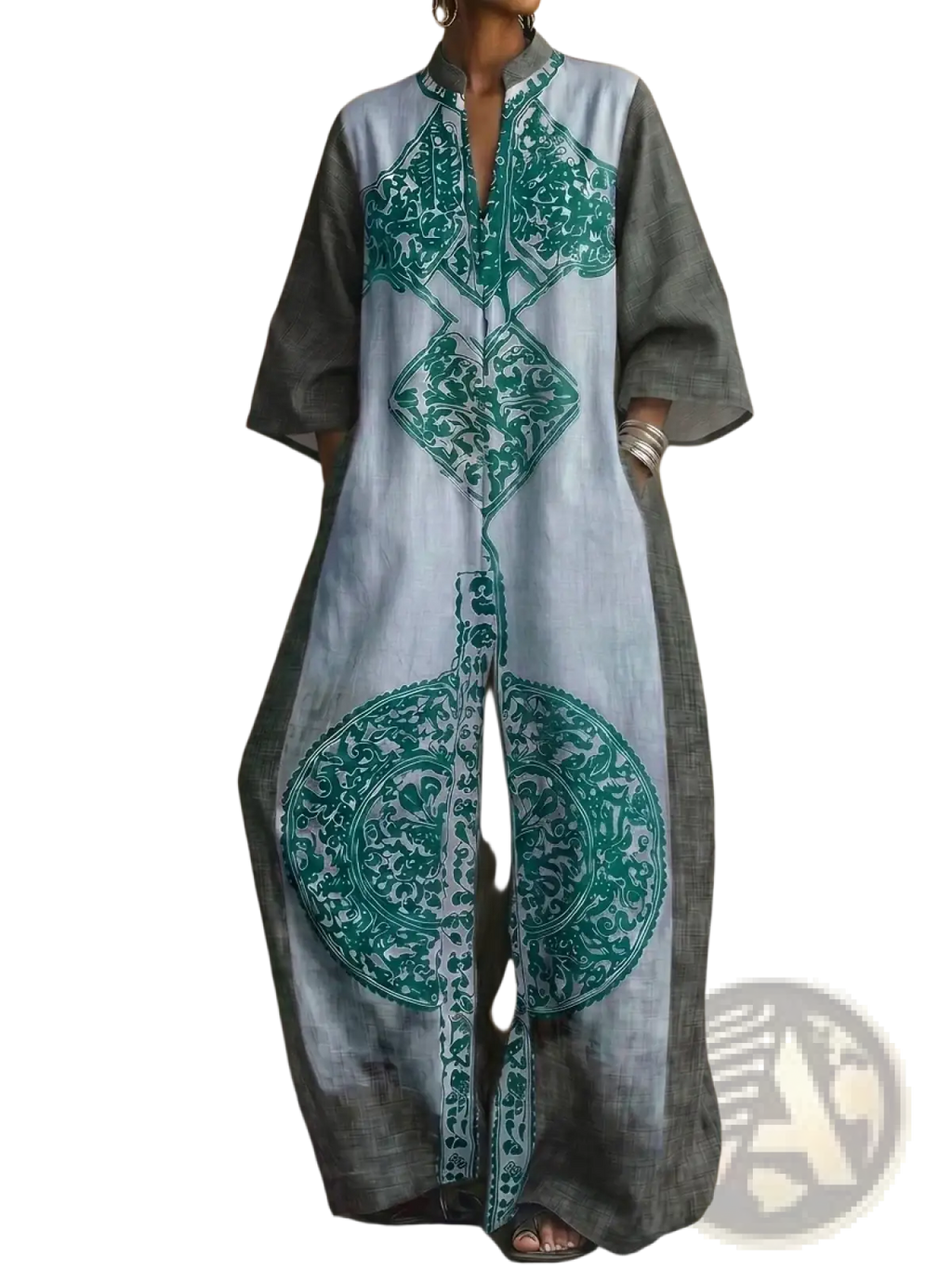 A long flowing light gray kaftan dress with bold teal geometric and floral embroidery on the front