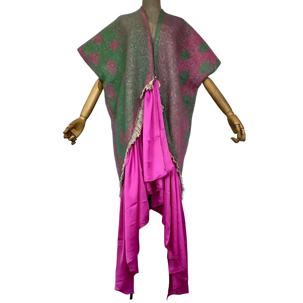 A vibrant asymmetrical winyi poncho with green and pink polka dots frayed edges and a bold magenta panel