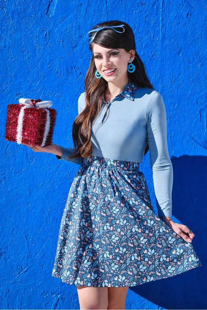 Red and white textured gift box with bow alongside a cozy blue long sleeve top with cat print collar displayed