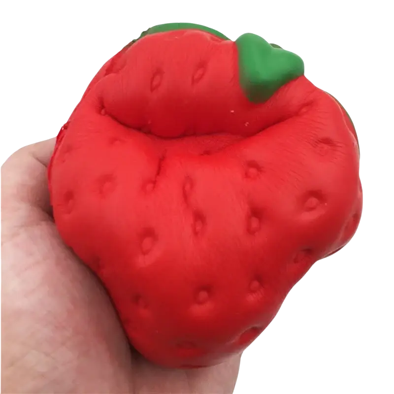 A vibrant red textured giant strawberry slow rising squishy stress relief toy with a green leafy top