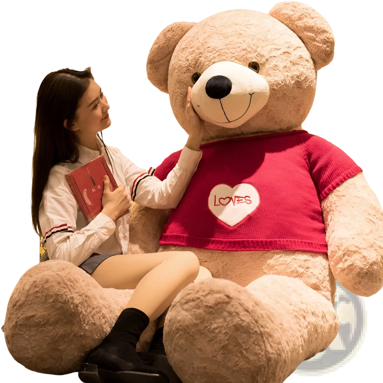 A plush tan giant teddy bear wearing a red knitted sweater with a white heart patch reading loves