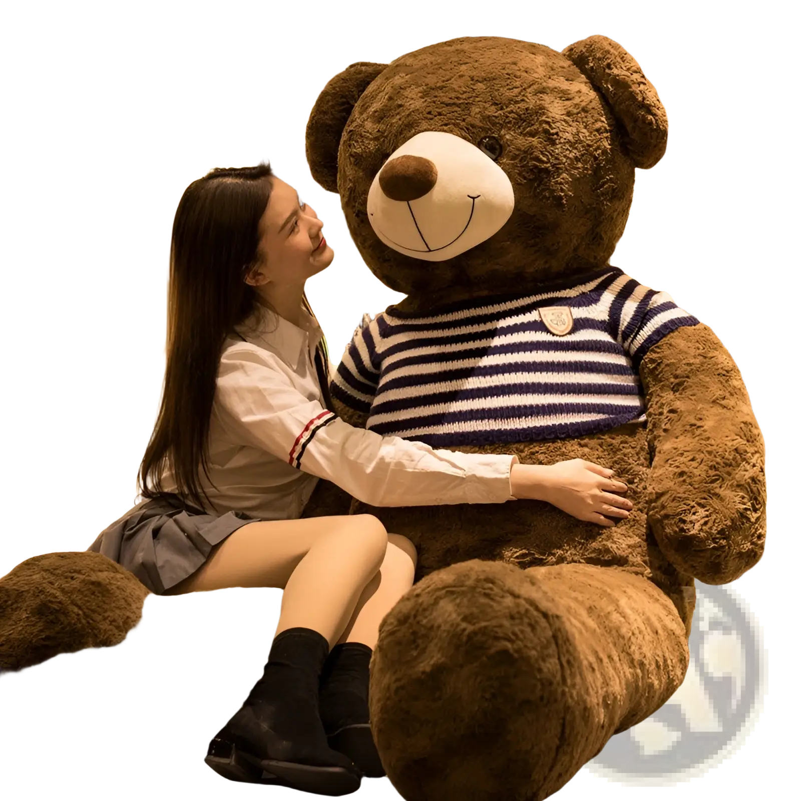 A plush brown giant teddy bear wearing a navy and white striped knit sweater with an embroidered chest patch