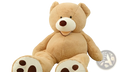 A plush tan giant teddy bear plush toy with a white snout and unfilled leather shell sitting on the floor
