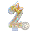 A glittery translucent number two birthday candle with yellow bow and bunny ears for festive celebrations