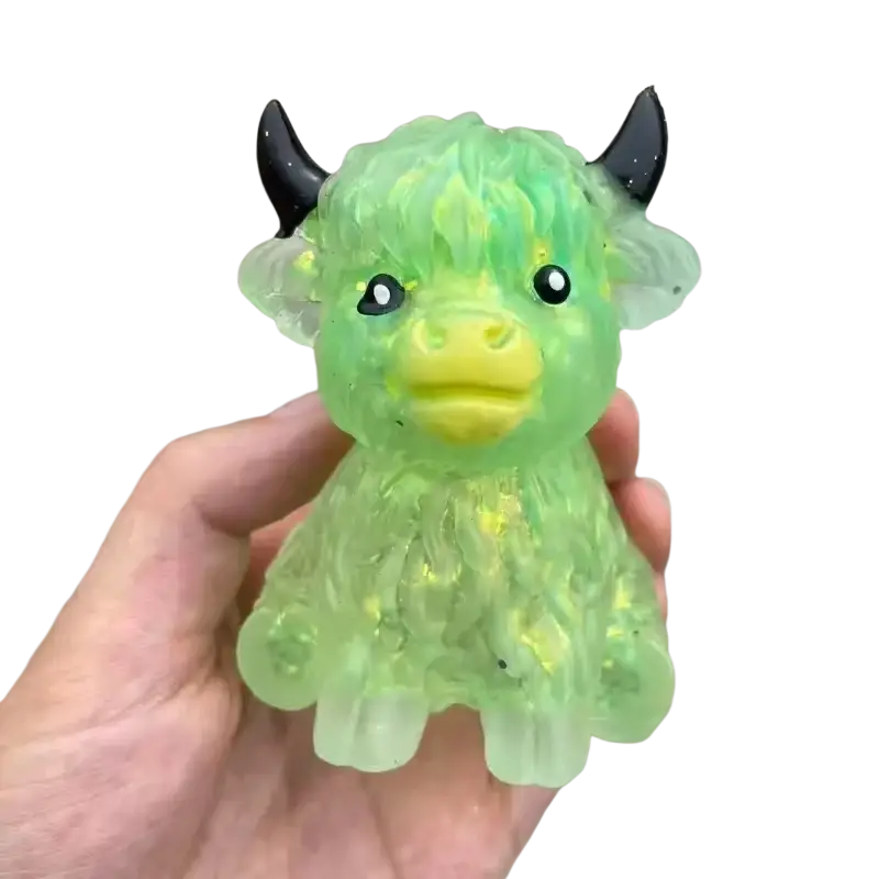 A translucent green highland cow slow rising squishy toy with fuzzy texture black horns and yellow snout