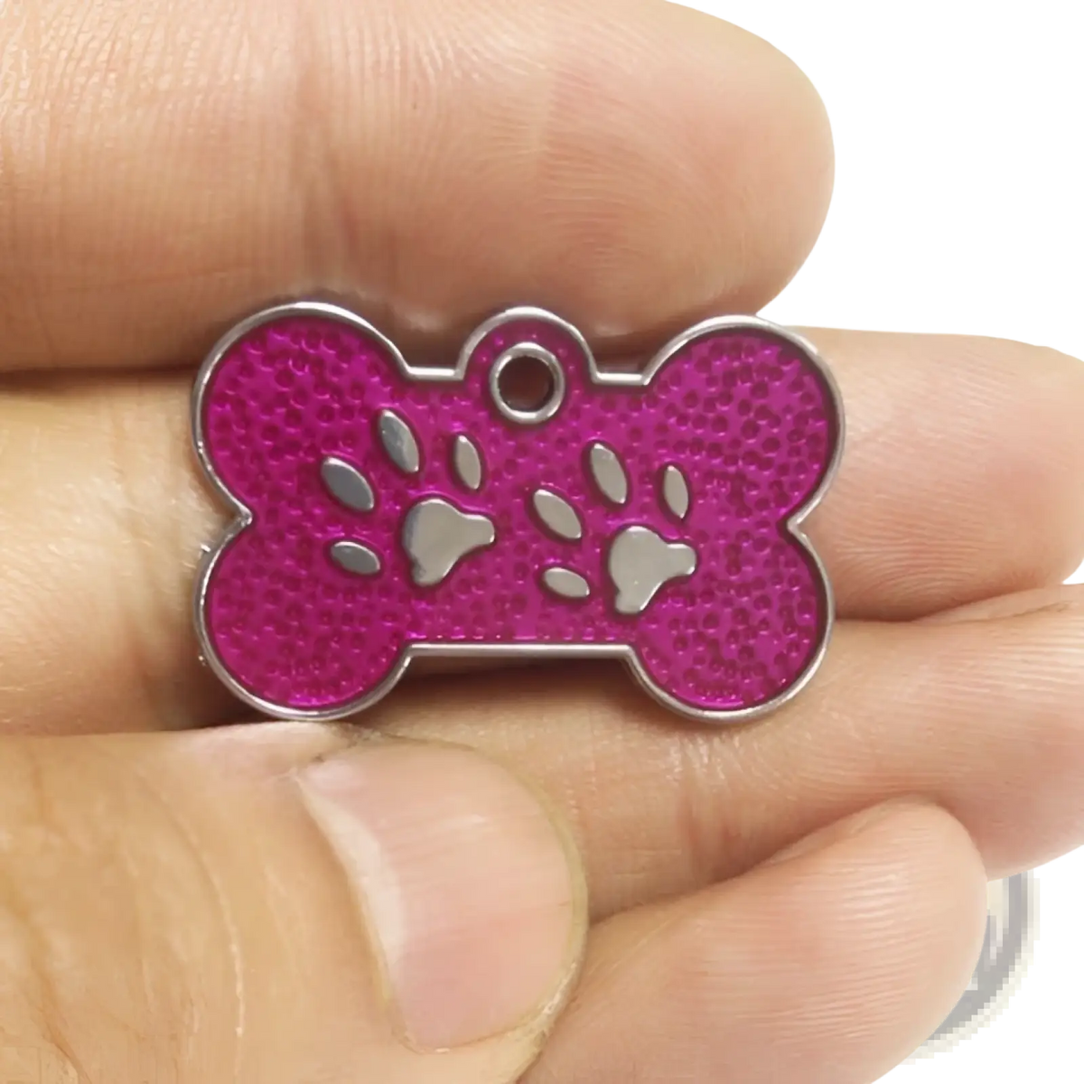 A vibrant pink glitter paw print metal dog tag in a bone shape with textured surface and silver paw cutouts