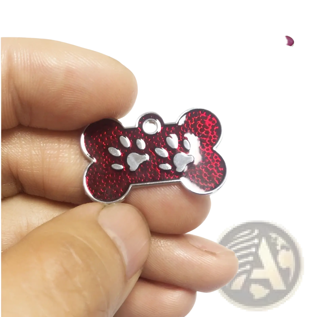 A red glittery bone-shaped metal dog tag with silver paw print designs and a metallic edge for pet identification