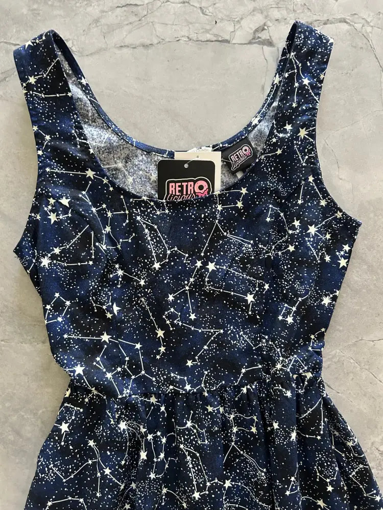 A navy blue sleeveless midi dress with white star constellation print and retro brand tag at the neckline with pockets
