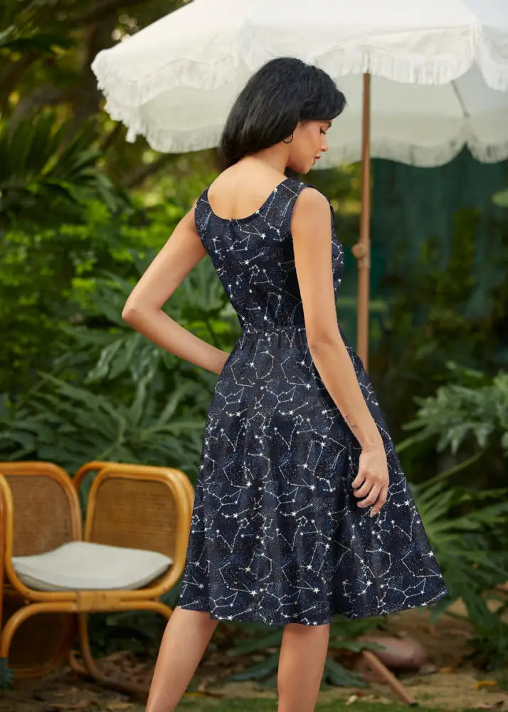 A navy blue glow in the dark constellation midi dress with pockets featuring a fitted bodice and flared skirt