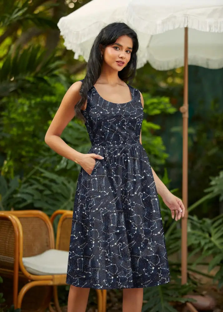 A navy blue sleeveless midi dress with glow in the dark constellation print square neckline and pockets