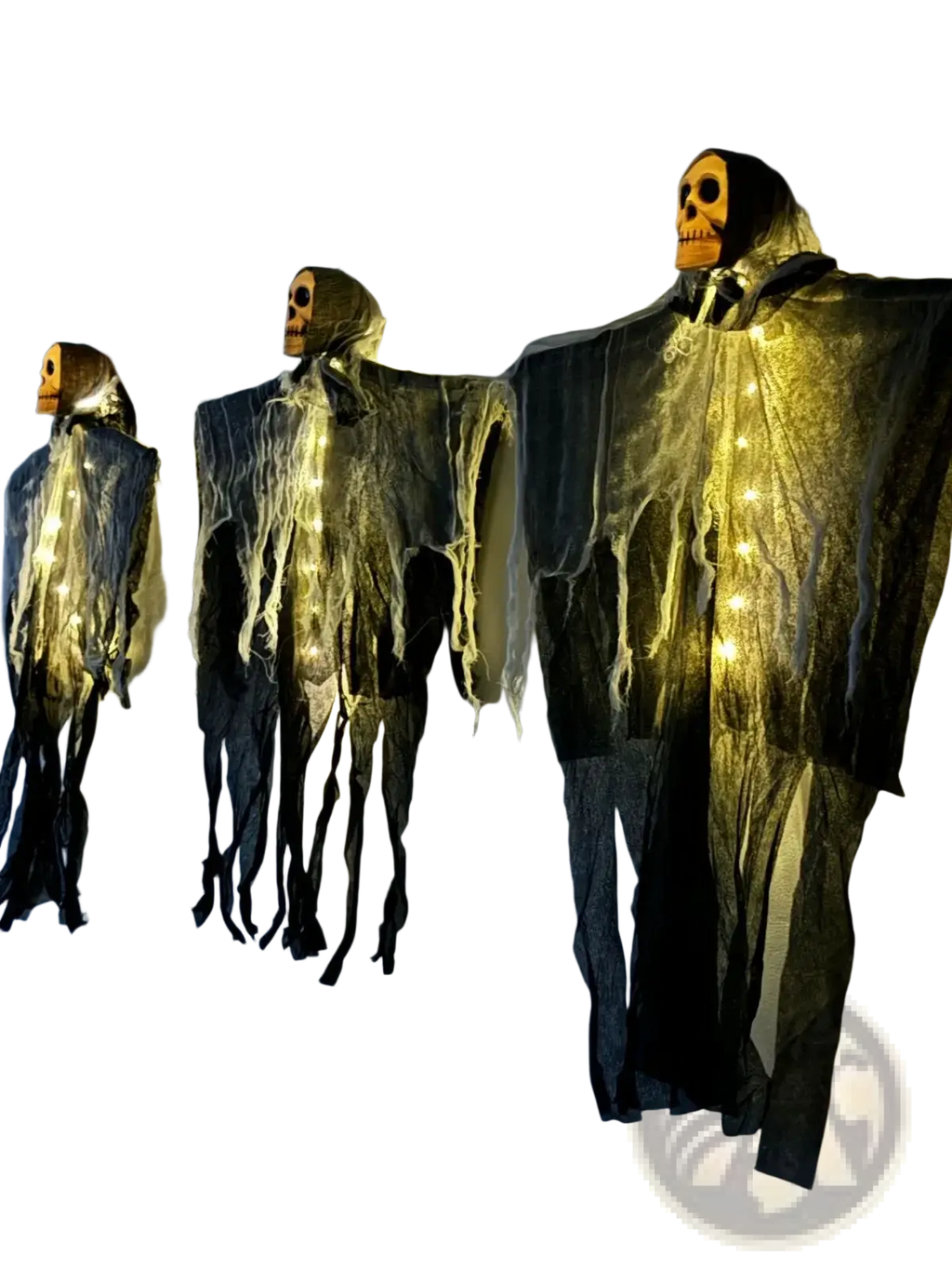Three halloween-themed hanging skeleton figures with glowing orange skull heads and dark tattered fabric with warm string lights