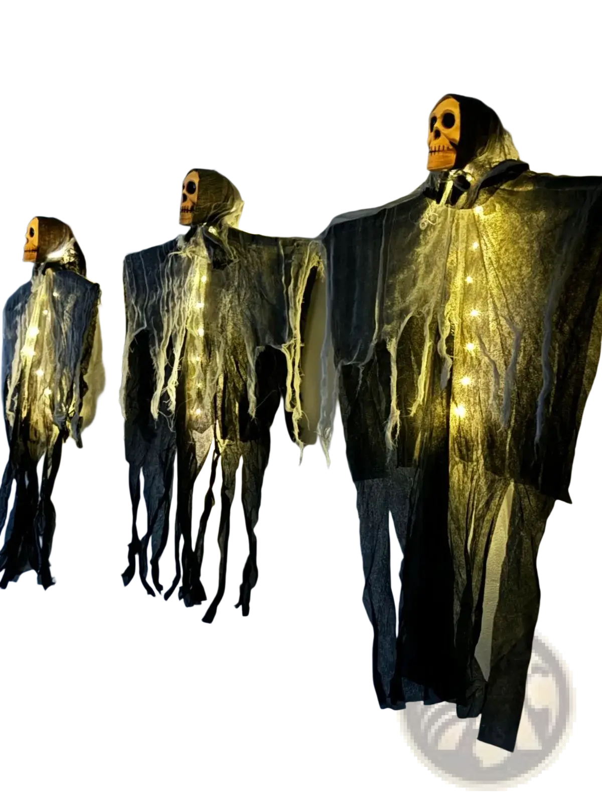 Three halloween-themed hanging skeleton figures with glowing orange skull heads and dark tattered fabric with warm string lights