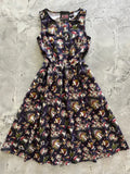 A sleeveless dark navy cotton midi dress with a whimsical gnome and mushroom print against a starry night sky