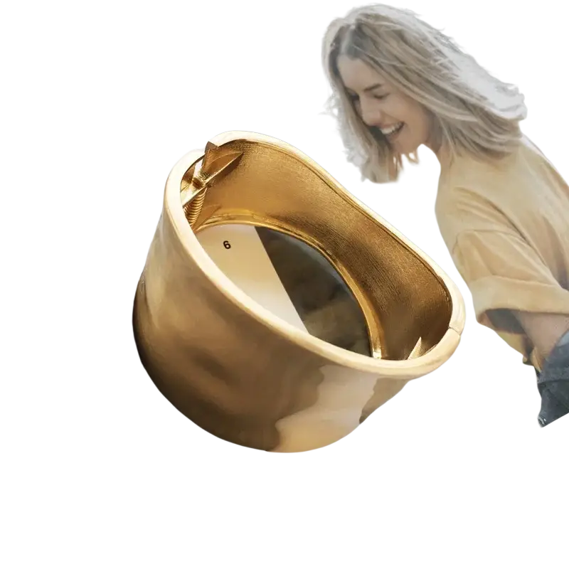 Gold asymmetric wide bangle bracelet with a textured gold-toned surface and small bow detail on the inside