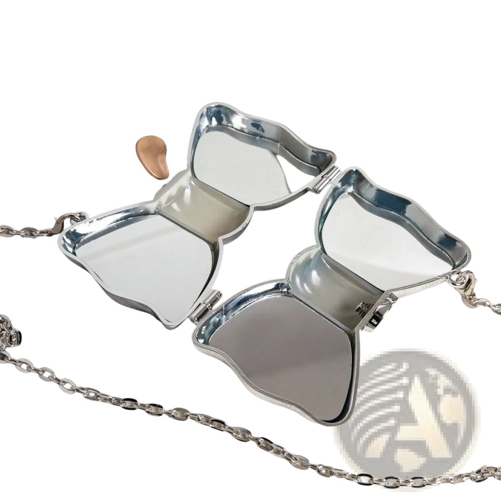 Silver butterfly-shaped compact mirror with reflective surfaces and chain strap shown with gold bow metal clutch crossbody bag