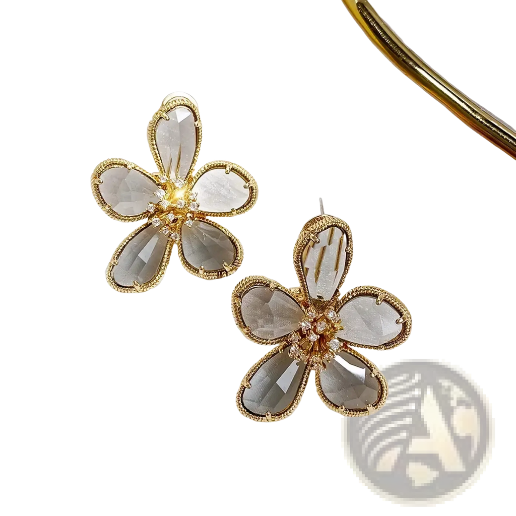 Gold flower crystal stud earrings with gold-toned metal, faceted gray crystal petals, and clear crystal center cluster