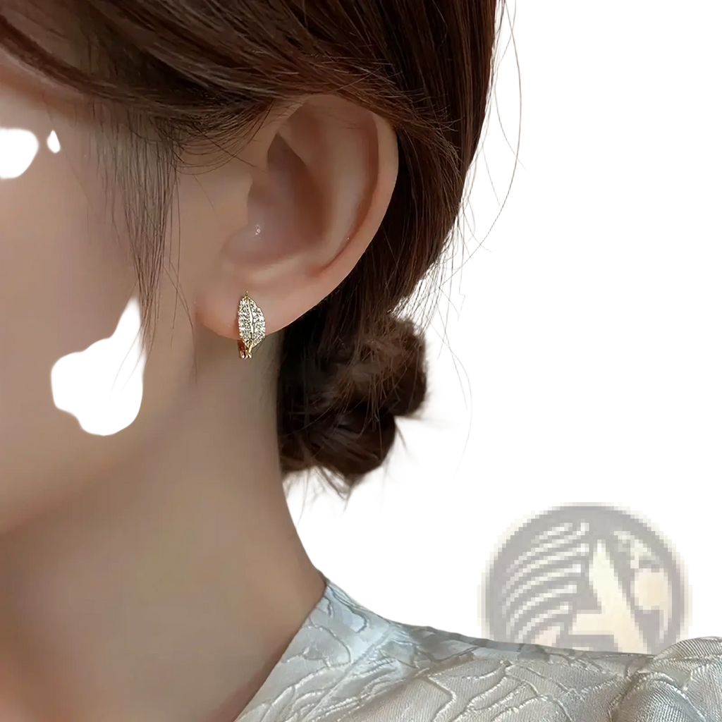 Gold-toned leaf-shaped hoop earring with sparkling clear crystals made of stainless steel for elegant wear