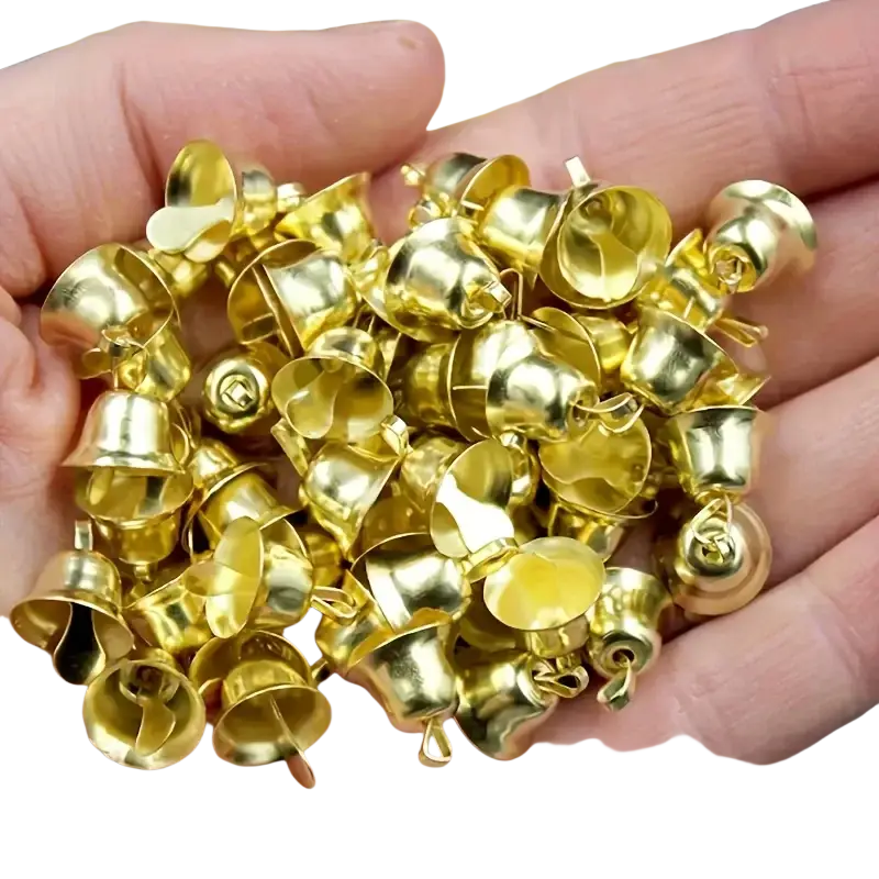 A hand holds a pile of small shiny gold metal sleigh bells with looped tops and hollow interiors 20 pcs