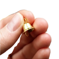 A tiny gold metal sleigh bell with a looped top held between fingers from a set of 20 pcs
