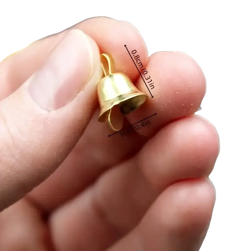 A tiny gold metal sleigh bell measuring 0.8cm by 1cm held between fingers for scale in a 20 pcs set
