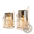 Gold metal spiral candle holder with glass cylinder features gold-toned metal and clear glass with modern wireframe design