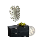 Silver metallic monstera leaf wall decor contrasting with the gold monstera leaf serving tray in a modern design
