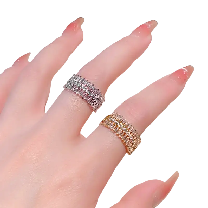 Two stacked multi-row gold-tone and silver-toned rings with baguette-cut crystals in a sleek modern design