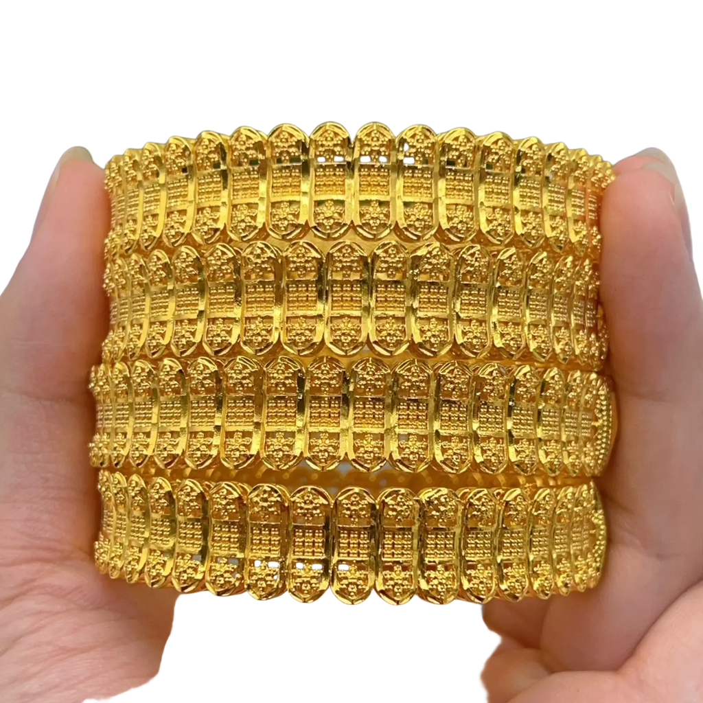 A stack of four gold plated zinc alloy bangles with intricate engraved patterns for elegant hand jewelry