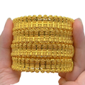 A stack of four gold plated zinc alloy bangles with intricate engraved patterns for elegant hand jewelry