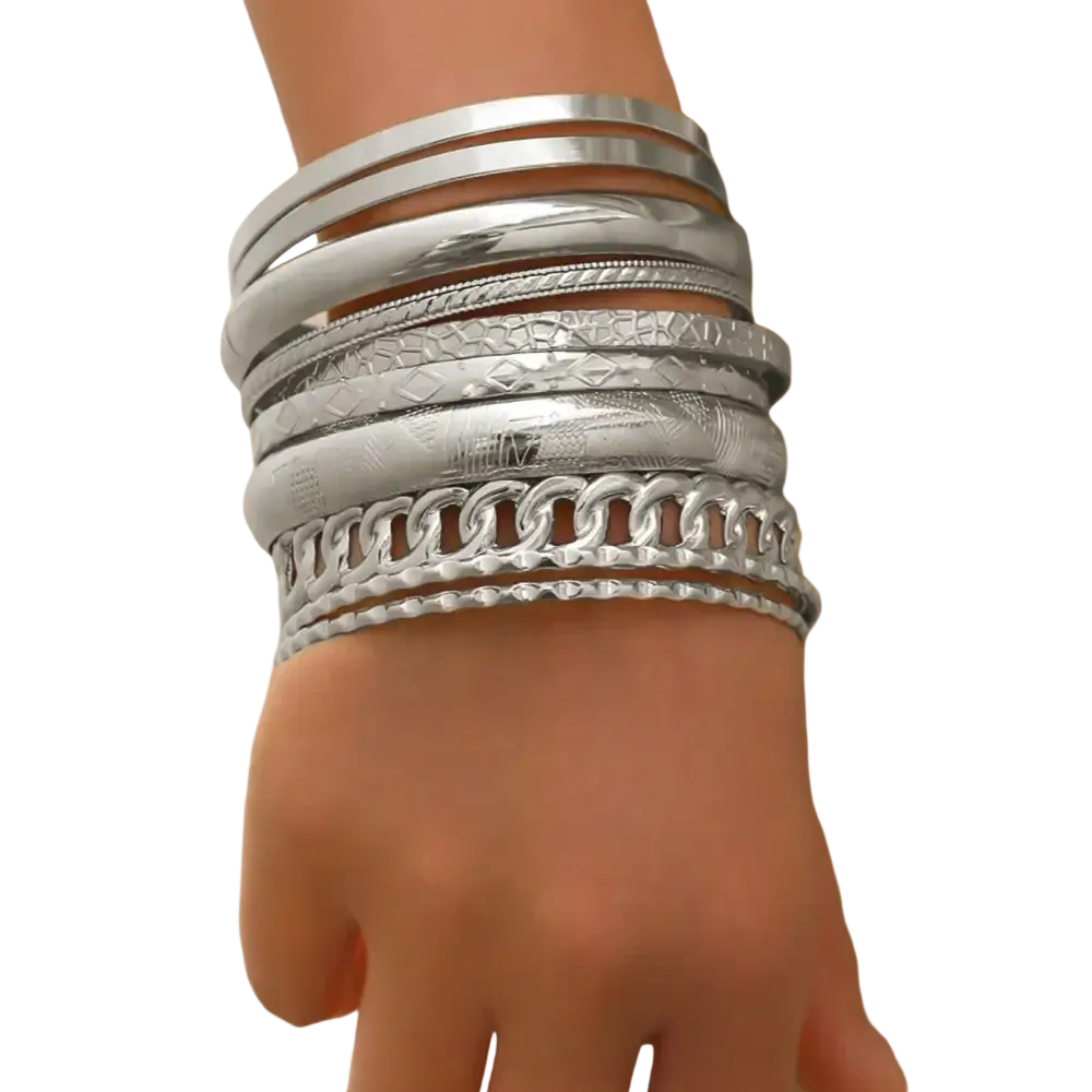 A stack of silver-toned gold punk bangle bracelets with varied textures including smooth hammered and chain-link designs