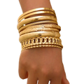 A stack of gold punk bangle bracelets featuring various textures including smooth, patterned, and chain-link styles