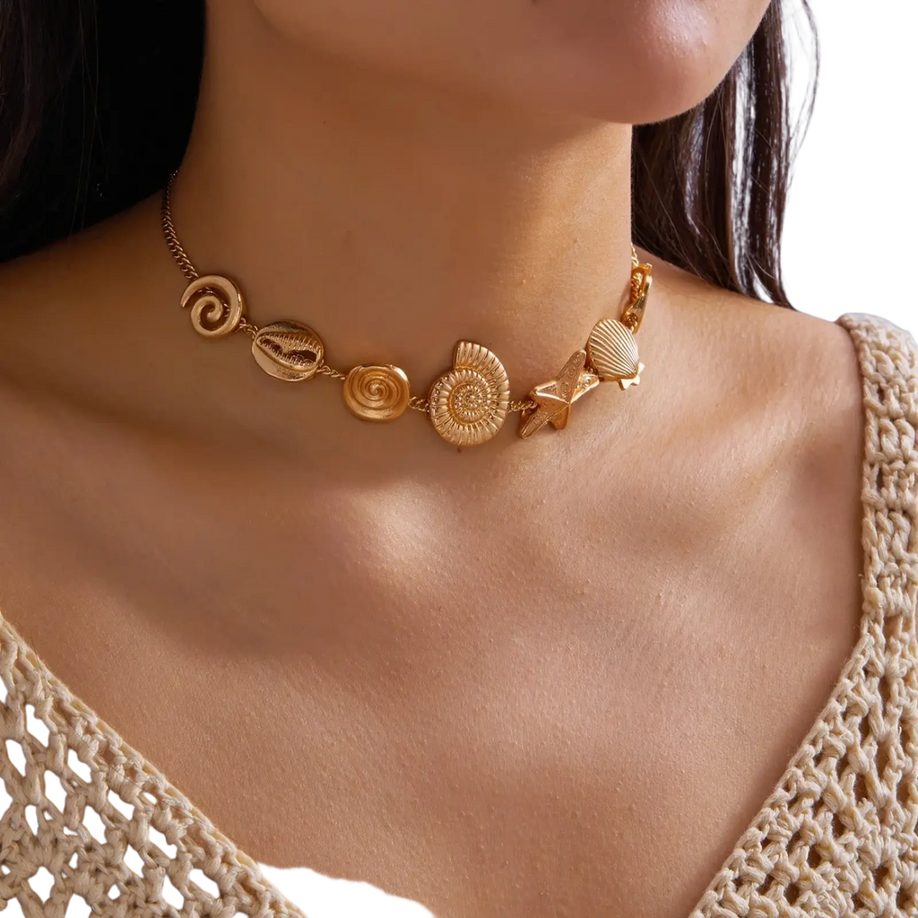 Gold-toned choker necklace featuring intricate seashell and starfish charms in a stylish beach-themed design