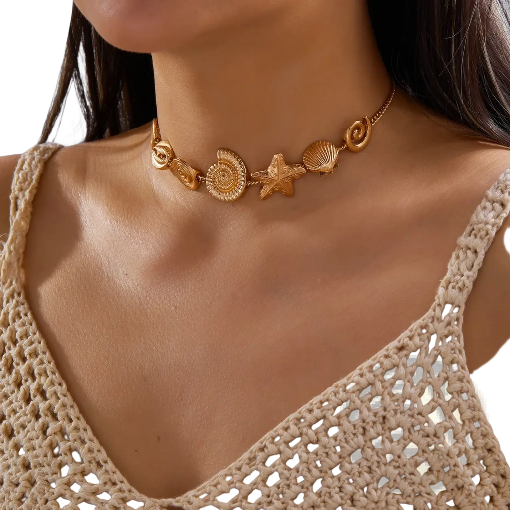 Gold-toned choker necklace featuring intricate sea-themed charms including starfish seashell and spiral shell
