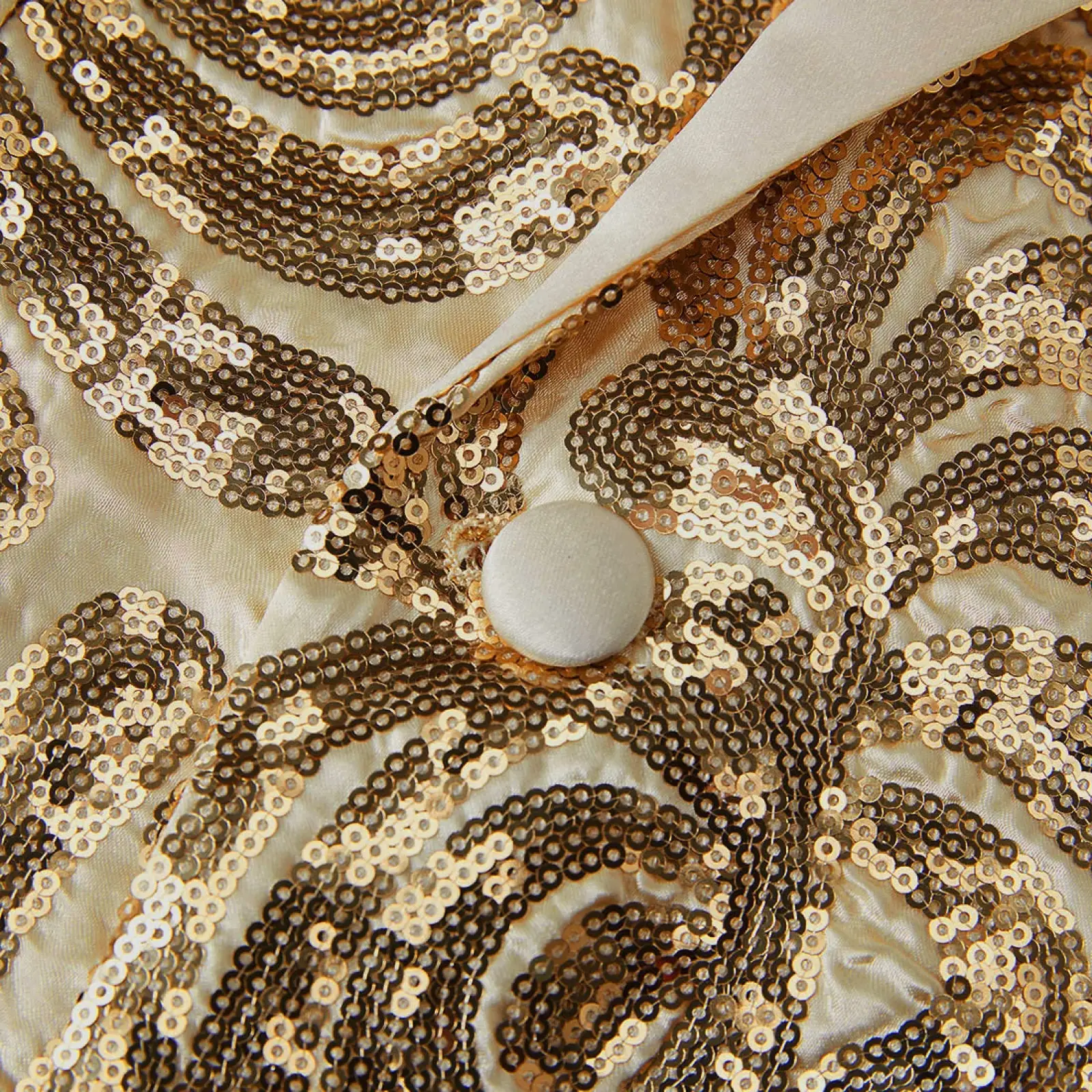 A gold sequin mens suit jacket in cream satin with intricate gold and bronze floral patterns and a white button fastening
