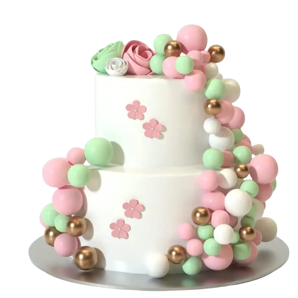 A two-tiered white cake decorated with pink mint green and gold foam balls and delicate pink flower toppers for birthday and wedding decor