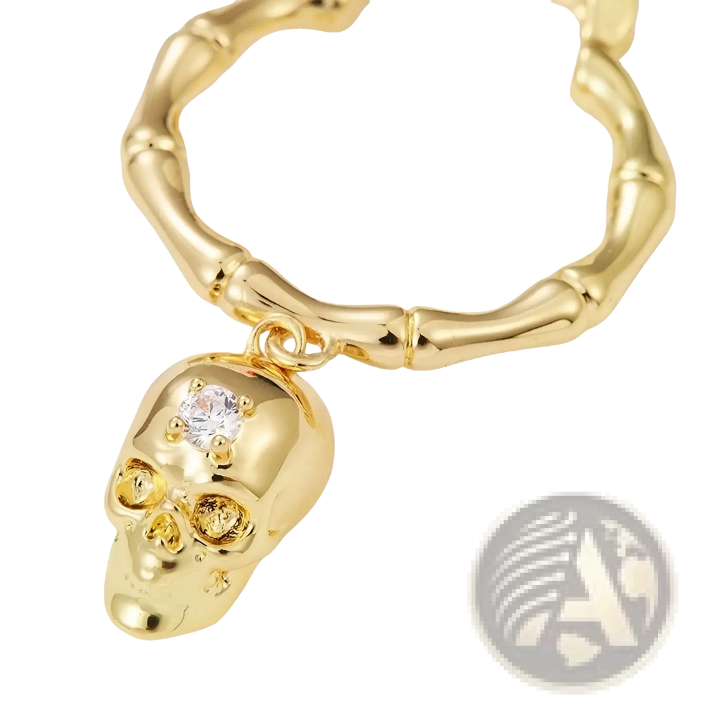 Gold skull tassel earrings featuring a gold-colored skull pendant with a clear crystal and bamboo-style chain