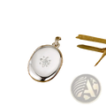 Silver oval locket pendant with delicate diamond-studded flower design featured in gold starburst locket necklace