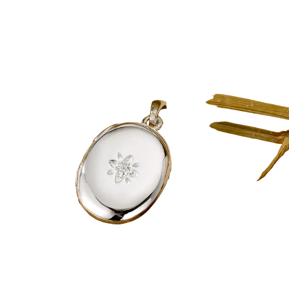 Silver oval locket pendant with delicate diamond-studded flower design featured in gold starburst locket necklace