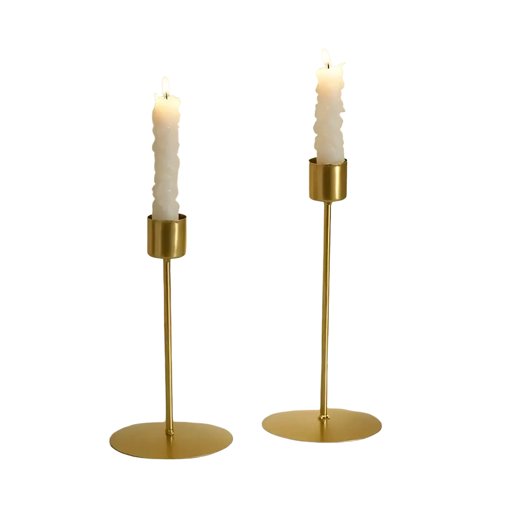 Two elegant gold-toned metal candle holders with slender stems and white textured taper candles for home decor
