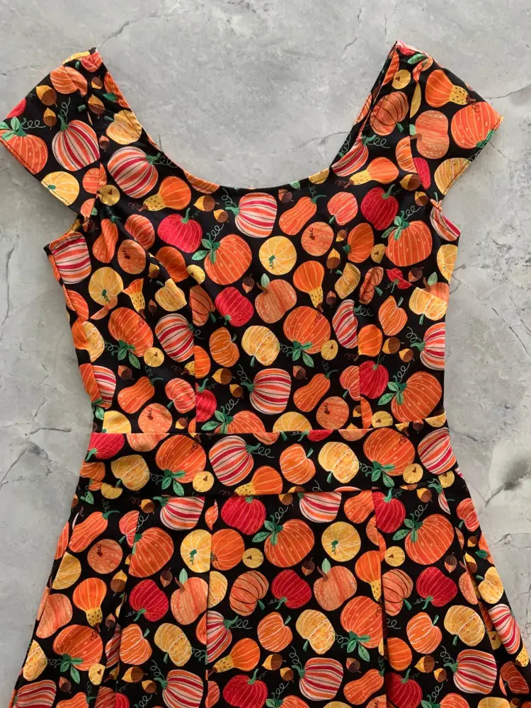 A black cotton gourdgeous margaret vintage a-line dress with vibrant pumpkin pattern in orange red and yellow with green stems