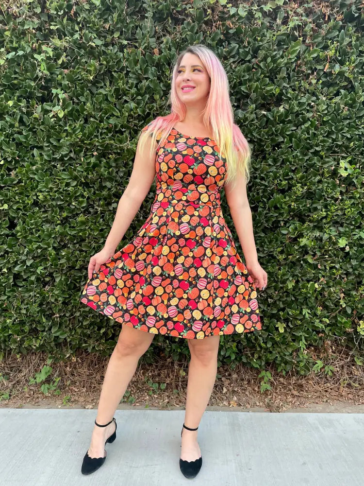 A vibrant sleeveless cotton a-line dress with orange and red pumpkin print on a dark background by Gourdgeous Margaret