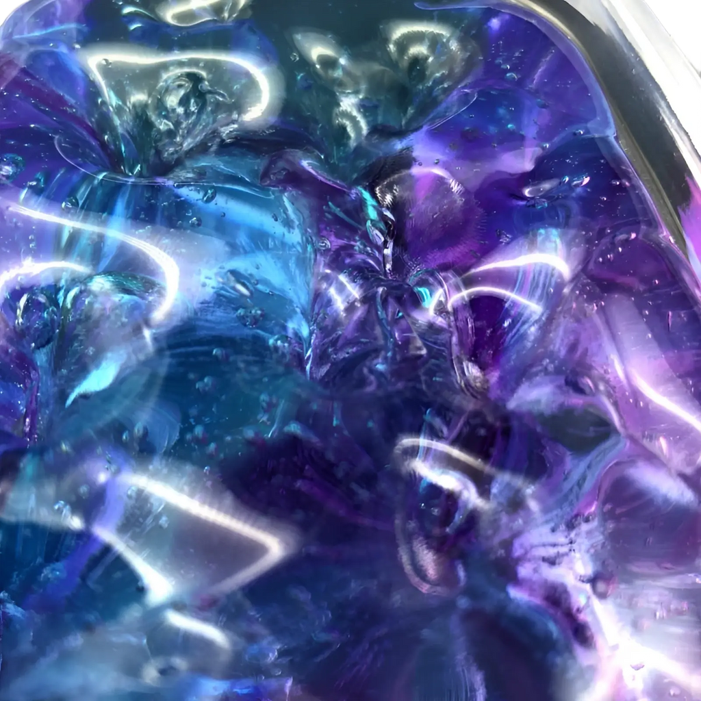 Gradient crystal mud slime blue and purple putty toy with translucent iridescent texture and swirling deep purple and blue hues