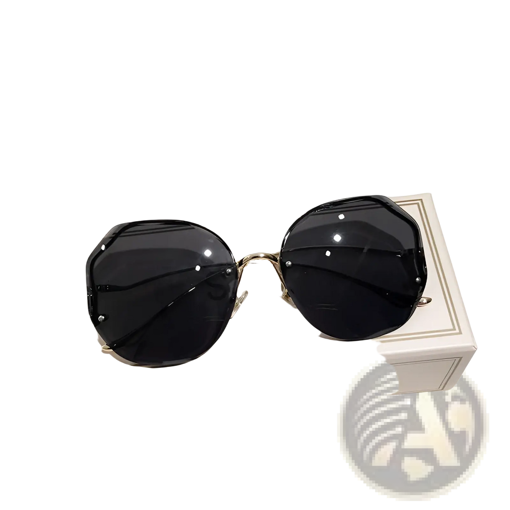 Black gradient oversized geometric sunglasses with gold metal frames resting on a beige branded box