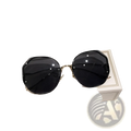 Black gradient oversized geometric sunglasses with gold metal frames resting on a beige branded box